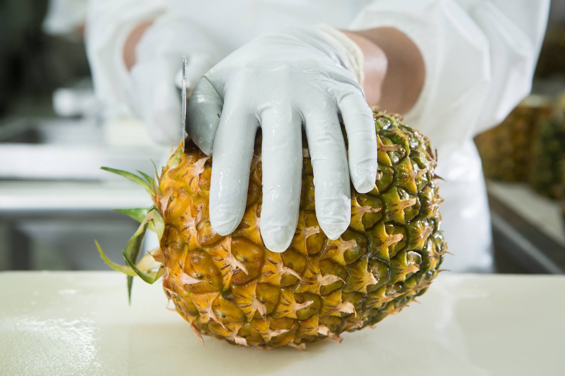 staff cutting pineapple
